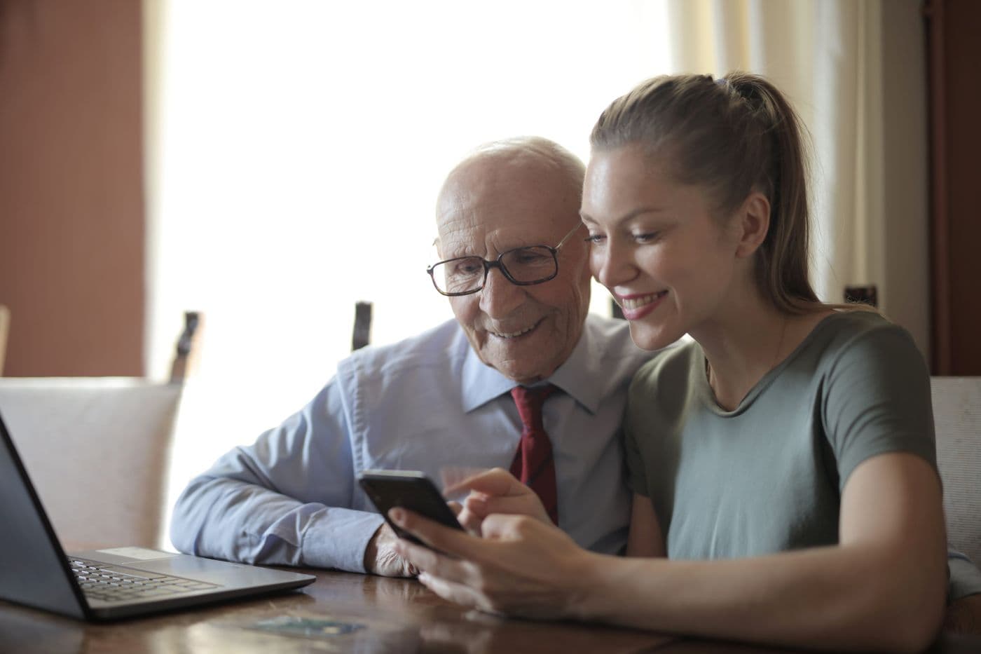 A younger person helping an older man use a phone