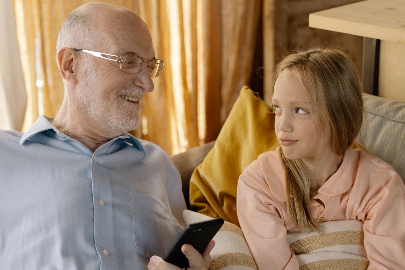 An older man and a child talking together on a sofa at home