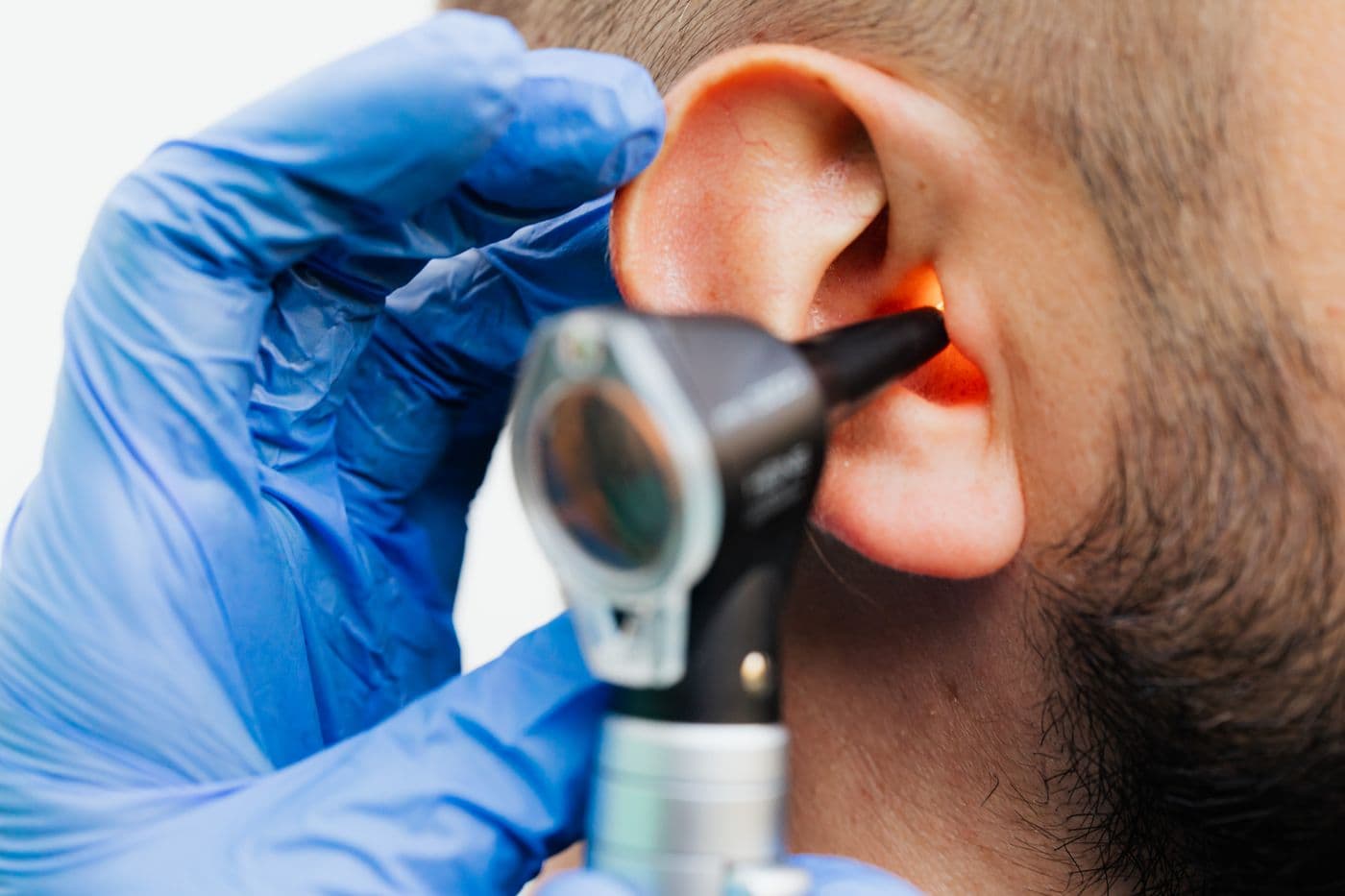 A hearing professional examining a patient's ear
